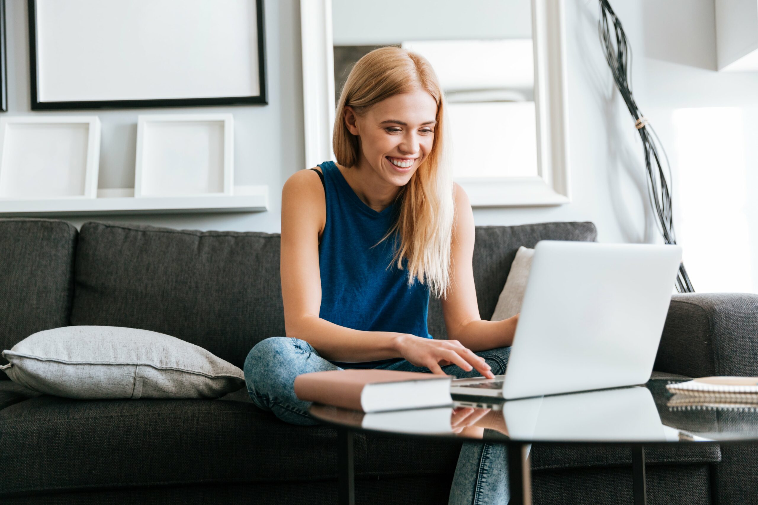happy-woman-sitting-sofa-using-laptop-home-min